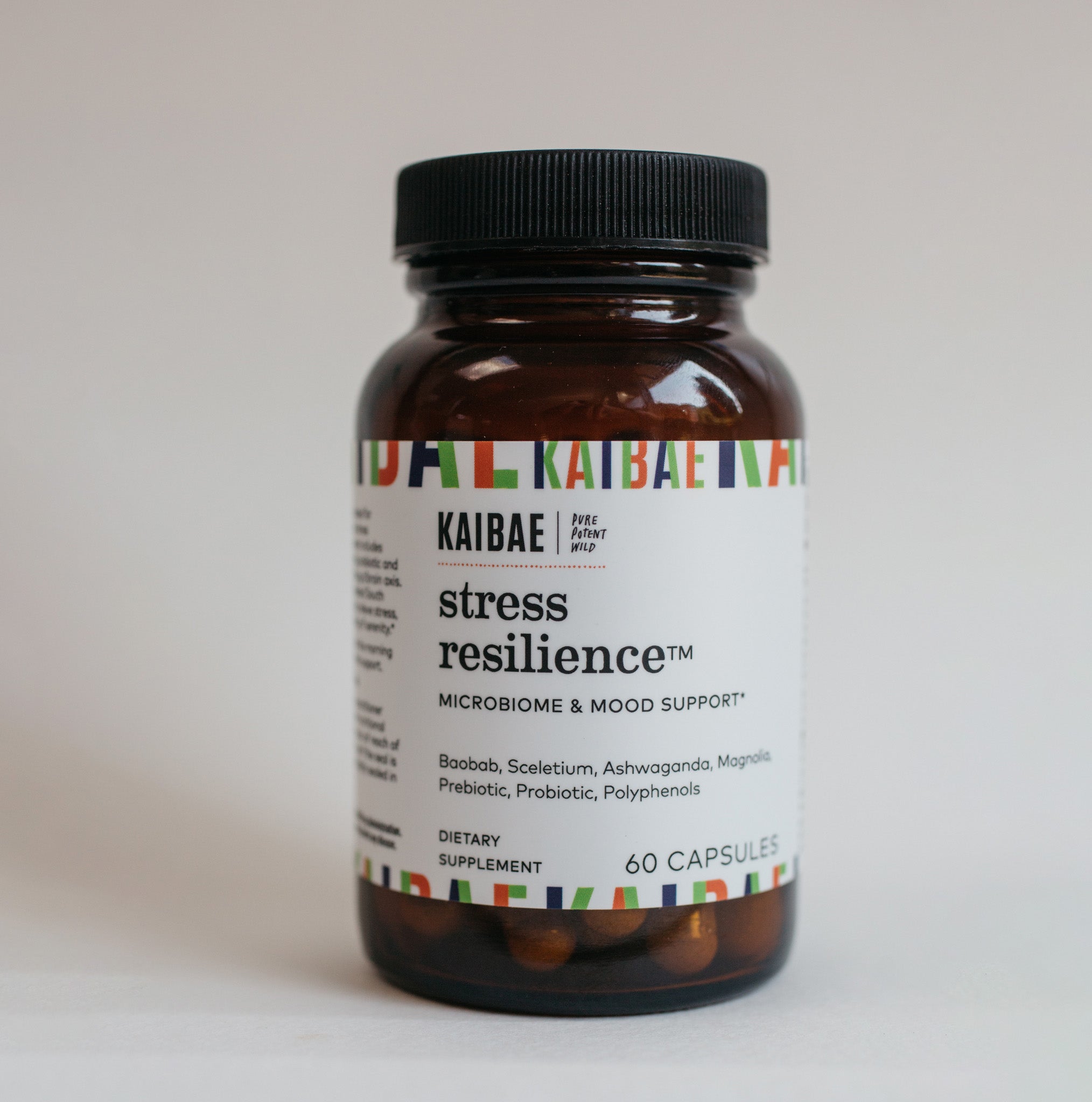 A close-up image of a supplement bottle labeled "KAIBAE stress resilience, for microbiome & mood support" with dietary contents  Baobab, Sceletium, Ashwaganda, Magnolia, prebiotic, probiotic and polyphenols listed, against a plain, light background.