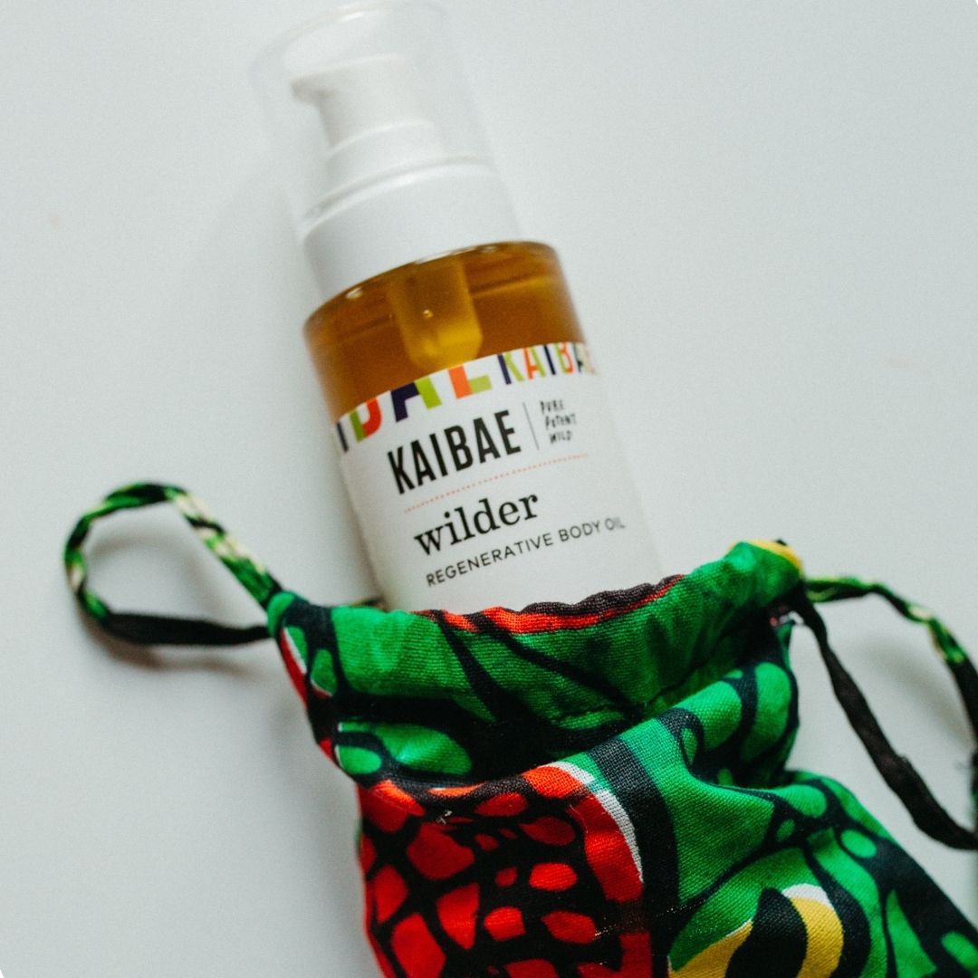 wilder body oil by kaibae in  a clear glass bottle in a colorful red green  and yellow pouch against a white backgroundpouch